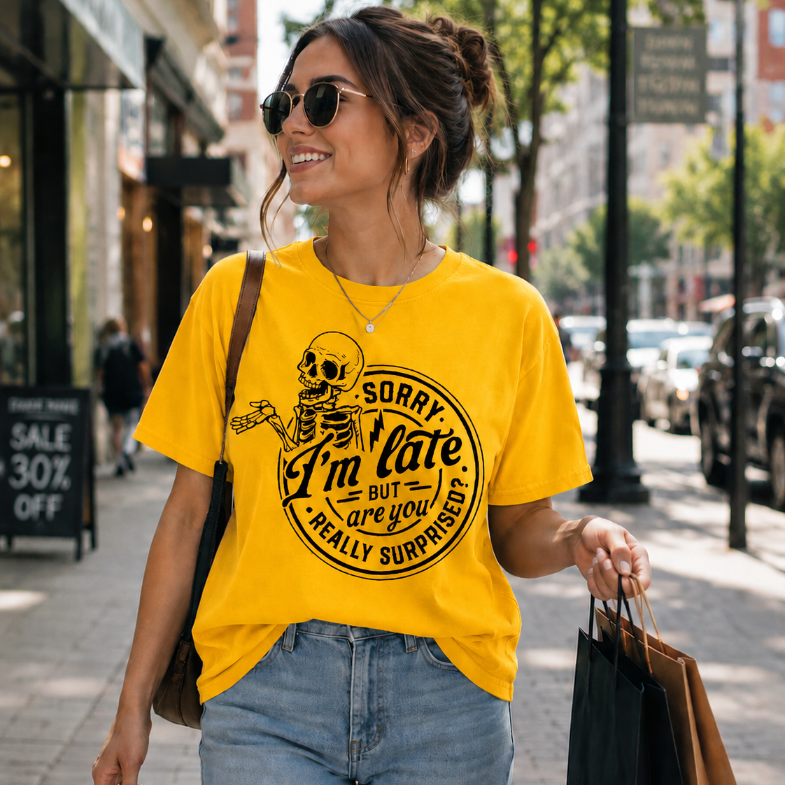 Woman walking down a street wearing a Daisy colored t-shirt with a skeleton graphic and text.