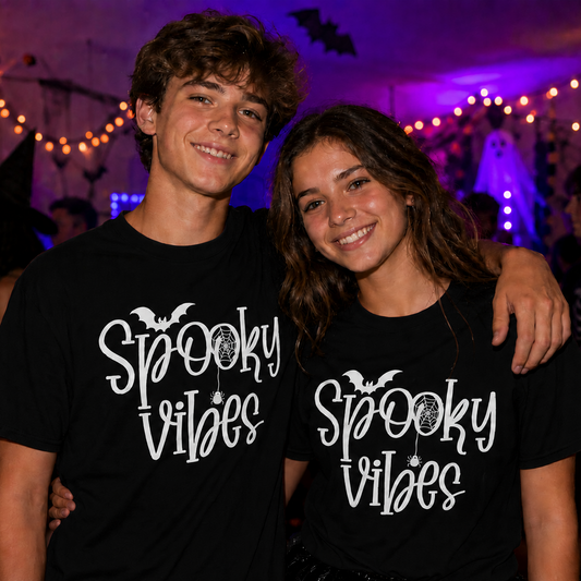 Two people wearing 'Spooky Vibes' black t-shirts in a Halloween-themed setting.