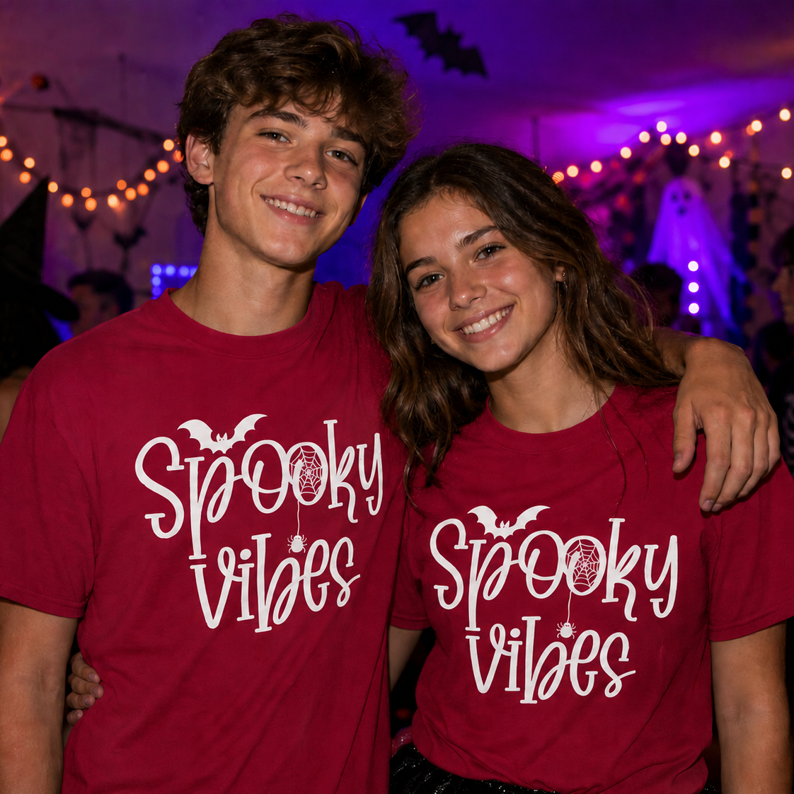 Two people wearing 'Spooky Vibes' crimson colored t-shirts at a Halloween party.