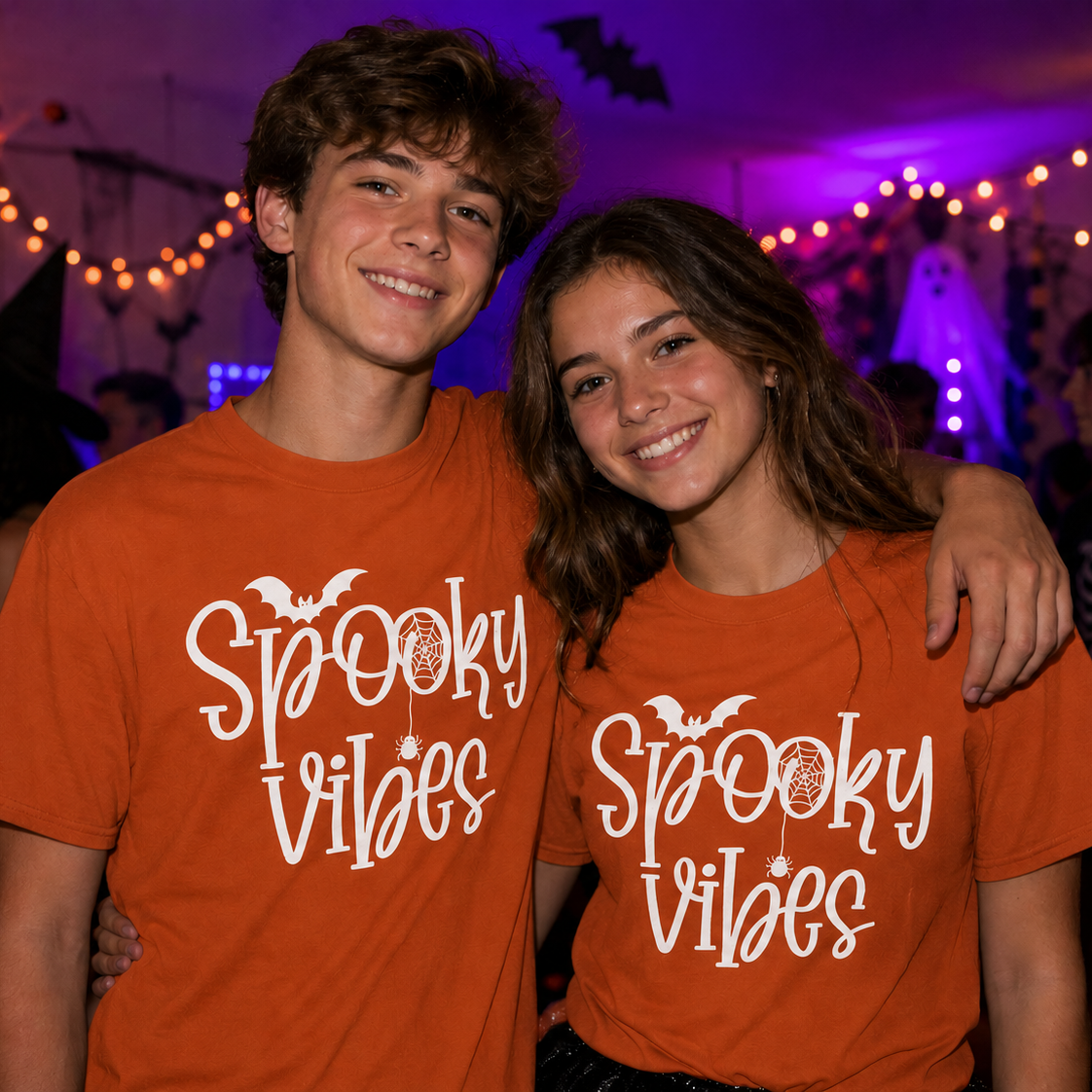 Two people wearing 'Spooky Vibes' yam colored t-shirts at a Halloween party.