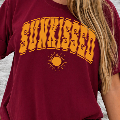 Cardinal red graphic t-shirt with 'SUNKISSED' in yellow text and a sun graphic.