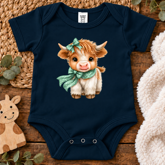 A Navy colored onesie(bodysuit) with a highland cow with a polka dot scarf and bow.