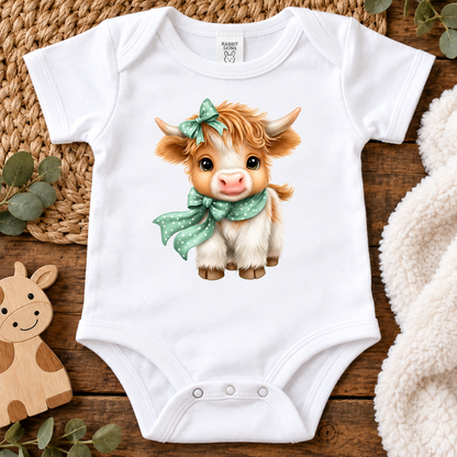 A white onesie(bodysuit) with a highland cow with a polka dot scarf and bow.