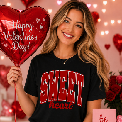 Woman wearing a 'Sweet heart' black shirt holding a Valentine's Day balloon with hearts and lights in the background.