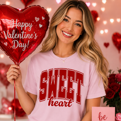Woman wearing a 'Sweet heart' light pink shirt holding a Valentine's Day balloon with hearts and lights in the background.