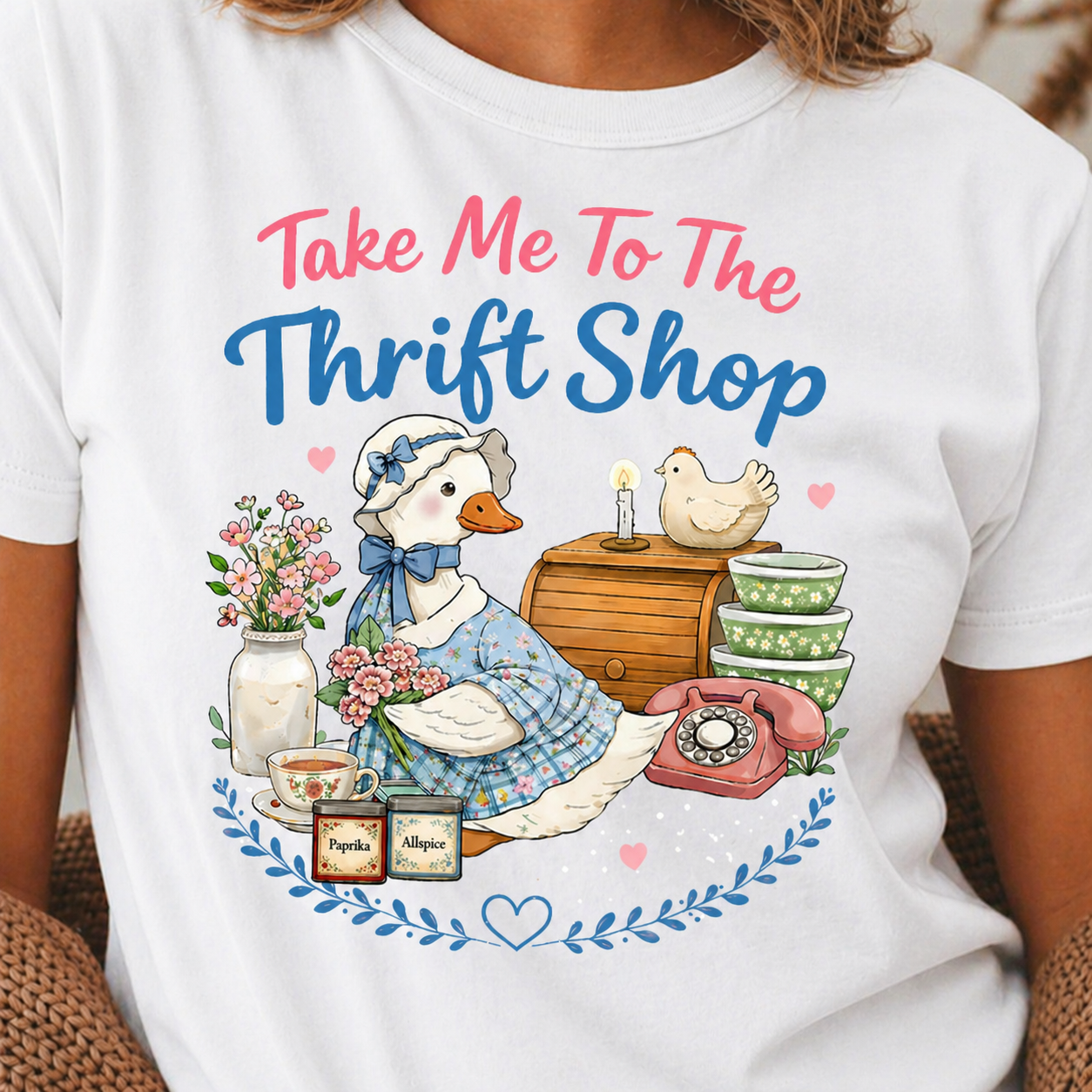 White t-shirt with a graphic of a duck in a thrift store setting and text 'Take Me To The Thrift Shop'.