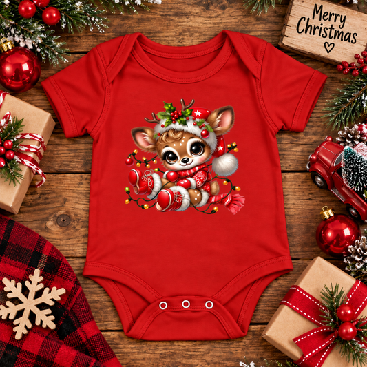 A red baby bodysuit with a festive Christmas dachshund graphic, styled in a flat-lay holiday setting with wrapped gifts, pine branches, and a wooden 'Merry Christmas' sign.