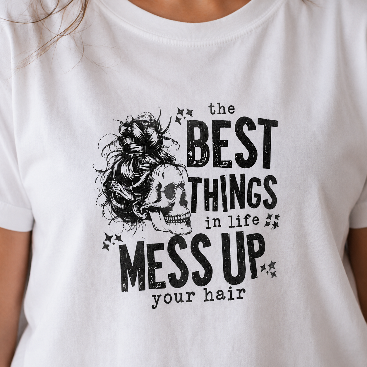 White t-shirt with black graphic and text 'the BEST THINGS in life MESS UP your hair' on a person wearing it.