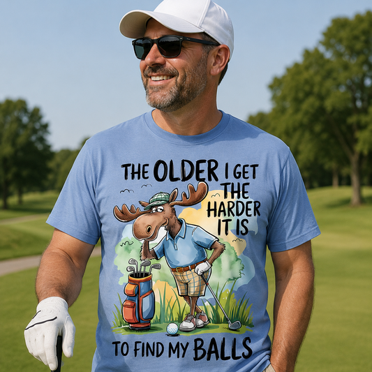 Man on a golf course wearing a blue t-shirt with a cartoon moose graphic and text.