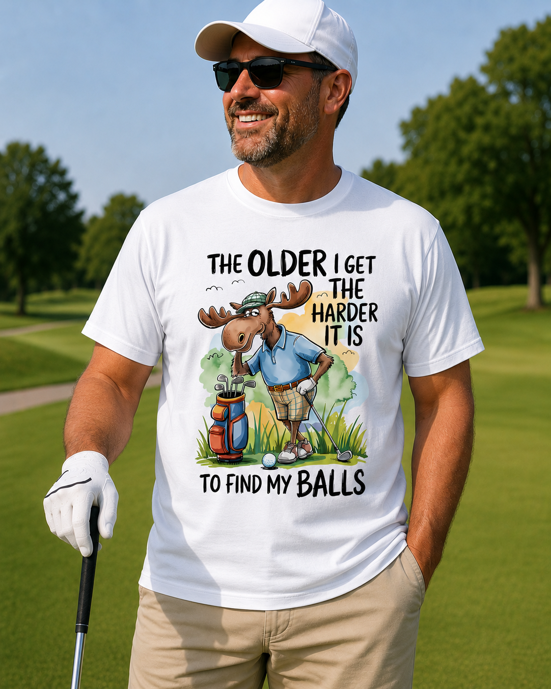 Man on a golf course wearing a white t-shirt with a moose graphic and text.