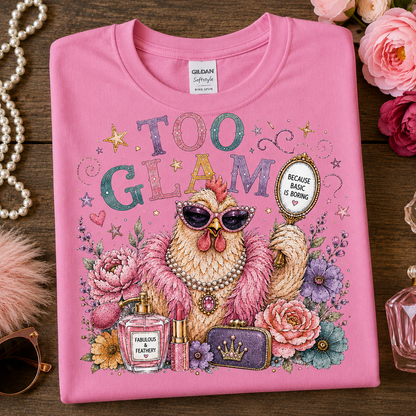 A azalea(pink) short-sleeve t-shirt with a colorful graphic of a glamorous chicken wearing sunglasses and a pearl necklace, surrounded by flowers and accessories, with the text 'TOO GLAM'. The shirt is laid flat on a wooden surface with decorative props including a pearl necklace, sunglasses, and pink roses.