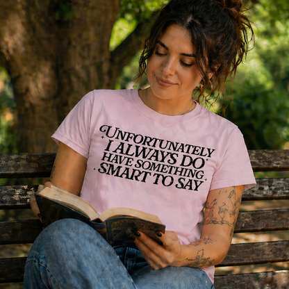 Woman reading a book on a bench in a park wearing a pink t-shirt with text.