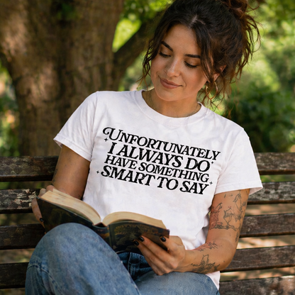 Woman reading a book in a park wearing a white t-shirt with text.