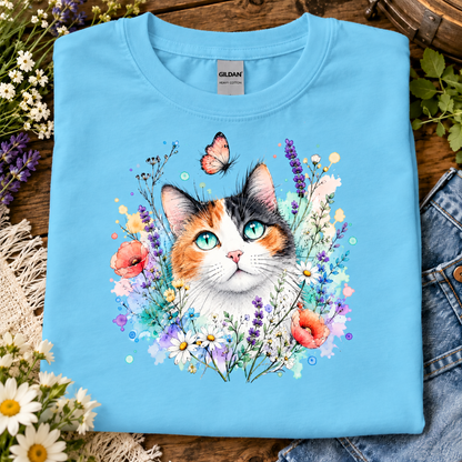 A sky blue colored t-shirt with a Calico cat surrounded by flowers and a butterfly graphic design
