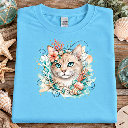 A sky blue colored t-shirt with a tan tabby cat surrounded by seashells
