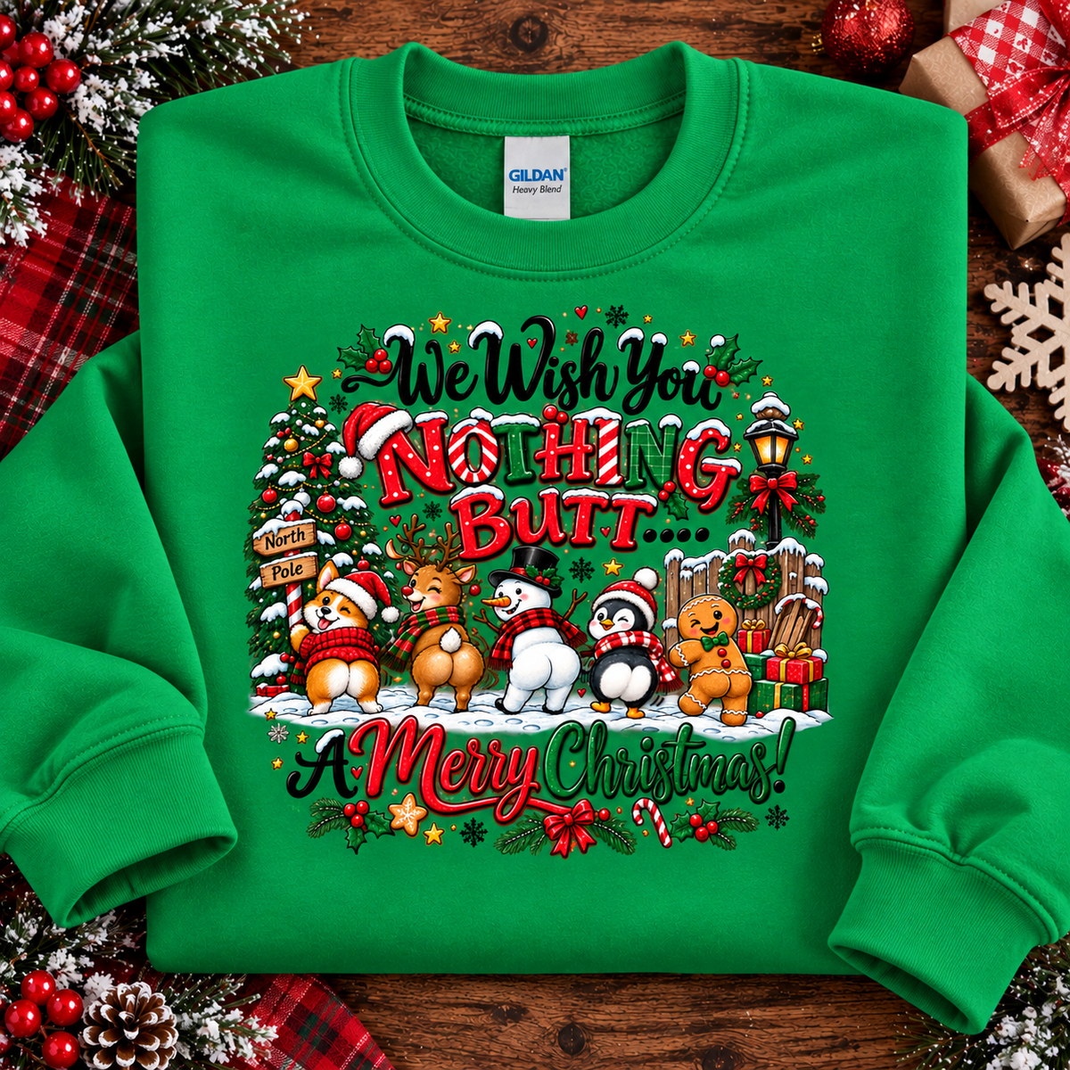 A irish green crewneck sweatshirt laid flat on a rustic wooden surface with holiday decorations around it. The front features a large, colorful Christmas graphic with cartoon animals and the text 'We Wish You NOTHING BUT A Merry Christmas!'.