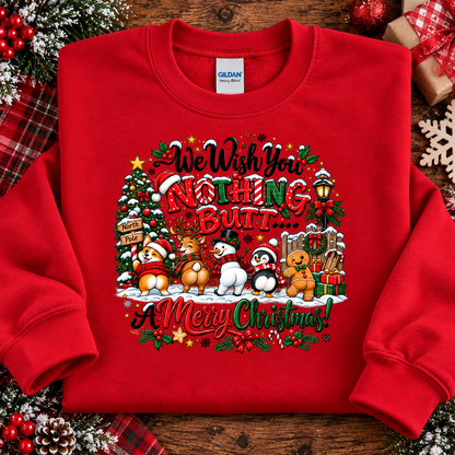 A red crewneck sweatshirt laid flat on a rustic wooden surface, surrounded by Christmas-themed props like plaid fabric, ornaments, and a wrapped gift. The sweatshirt features a large, colorful graphic with the text 'We Wish You Nothing But.