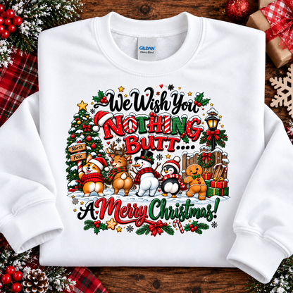 A white crewneck sweatshirt laid flat on a rustic wooden surface, surrounded by Christmas-themed props like a red plaid scarf, pinecones, and a wrapped gift. The sweatshirt features a colorful graphic with the text 'We Wish You Nothing But.