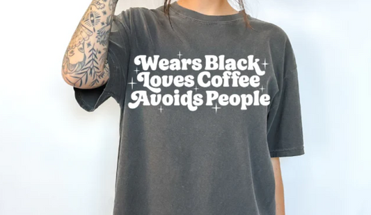 “Wears Black, Loves Coffee, Avoids People” sarcastic text graphic printed on a t-shirt.