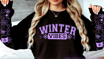 Black sweatshirt with 'Winter Vibes' text and winter-themed graphics worn by a person.