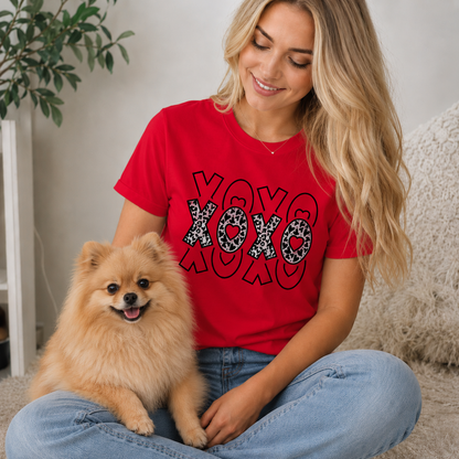 Woman wearing a red 'XOXO' t-shirt sitting with a small dog indoors.
