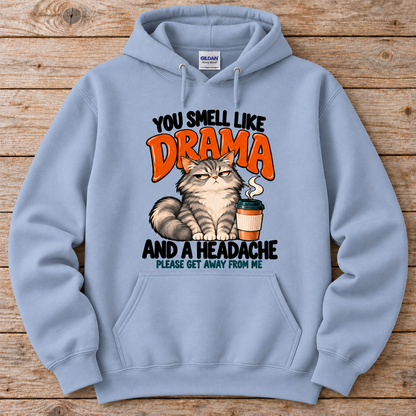 A light blue crewneck hoodie featuring a humorous graphic print of a grumpy cat next to a coffee cup, with the text 'YOU SMELL LIKE DRAMA AND A HEADACHE PLEASE GET AWAY FROM ME'. 