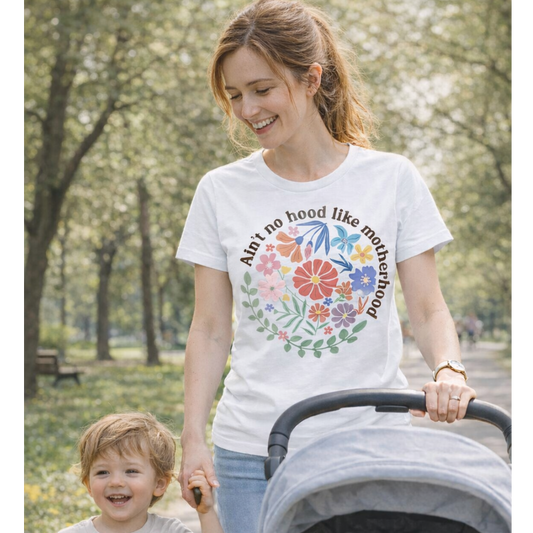 Woman pushing a stroller with a child, wearing a white t-shirt with colorful floral design and text.