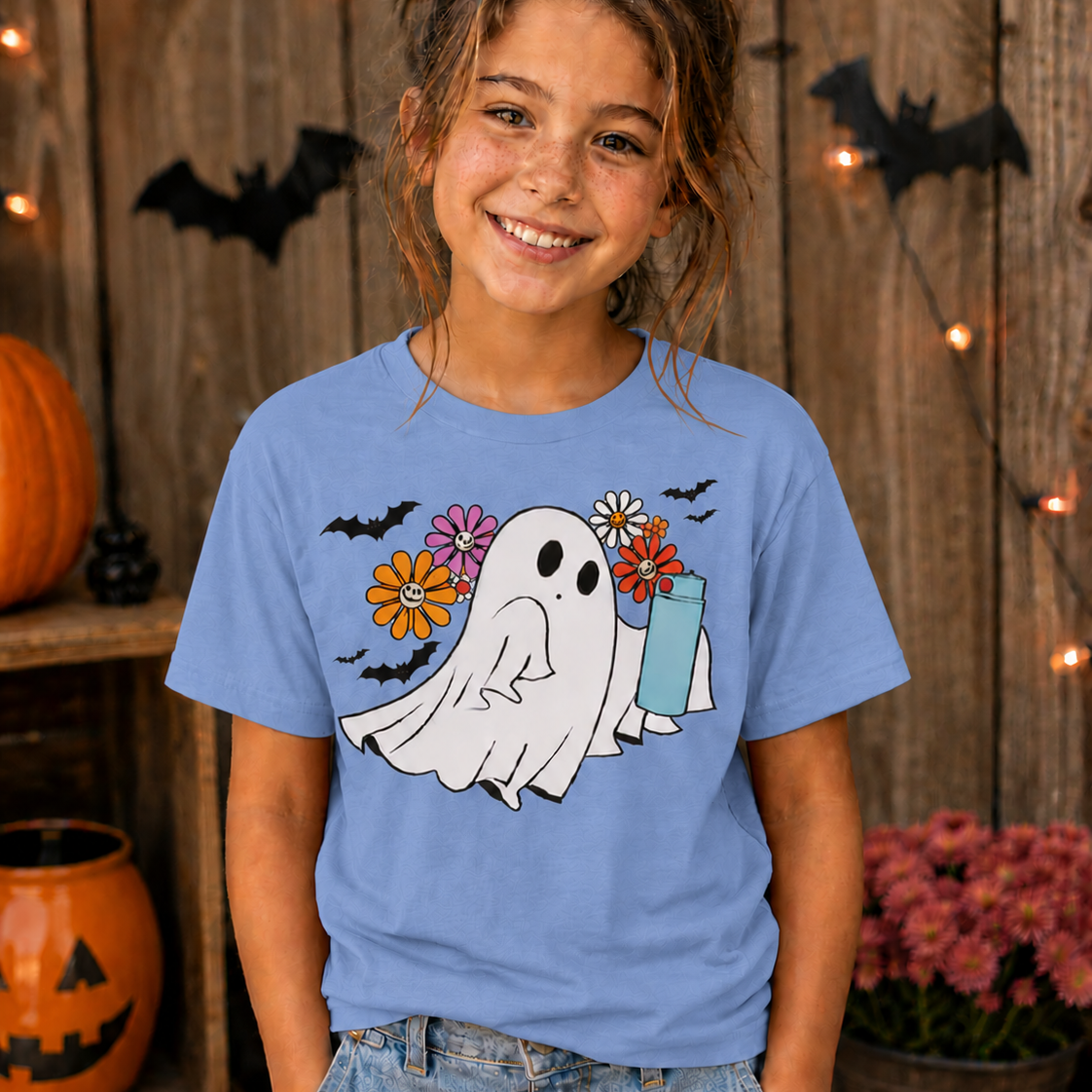 Girl wearing a blue t-shirt with a ghost graphic design with flowers and bats