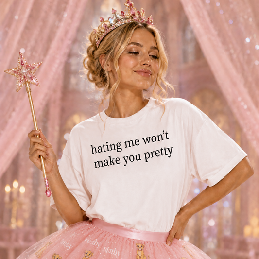 Woman in a white t-shirt with text and pink skirt holding a wand in a fairy-tale setting
